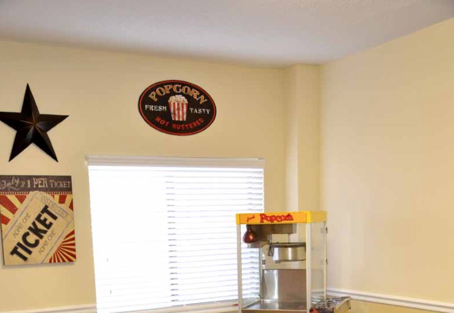 A cozy kitchen corner featuring a popcorn machine and a vintage-style popcorn sign on the wall.