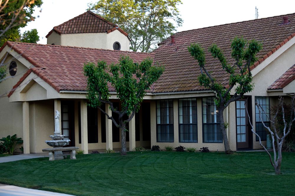 A suburban house with a tiled roof, large windows, and a neatly maintained lawn.