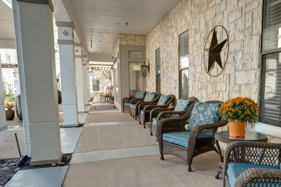 A cozy porch with wicker chairs lined up along a stone wall, featuring a decorative star.