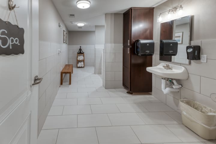A clean and modern public restroom with tiled flooring, mirrors, a sink, and hand dryers.
