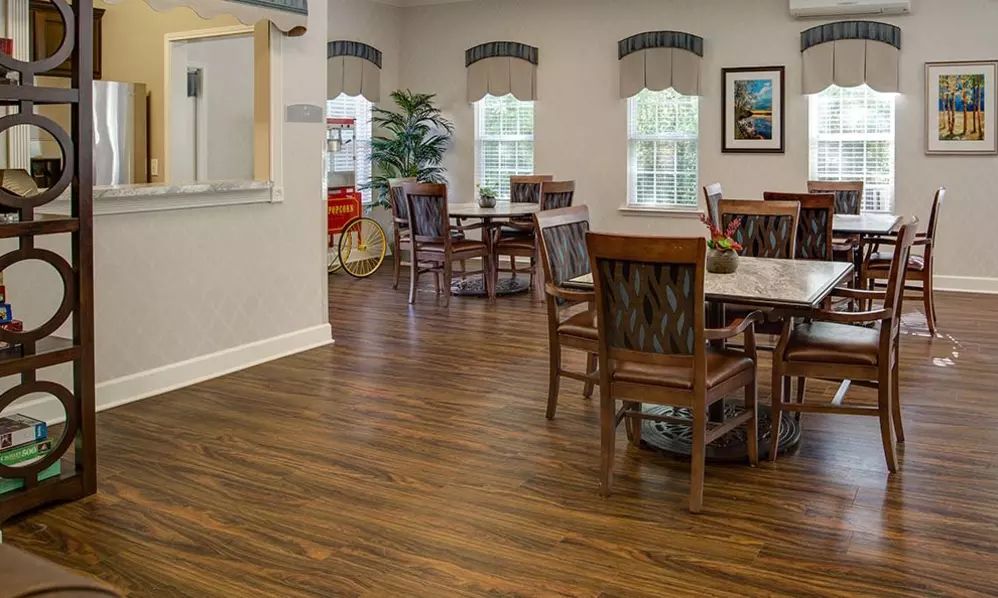 A well-lit dining area with wooden floors, tables, and chairs.