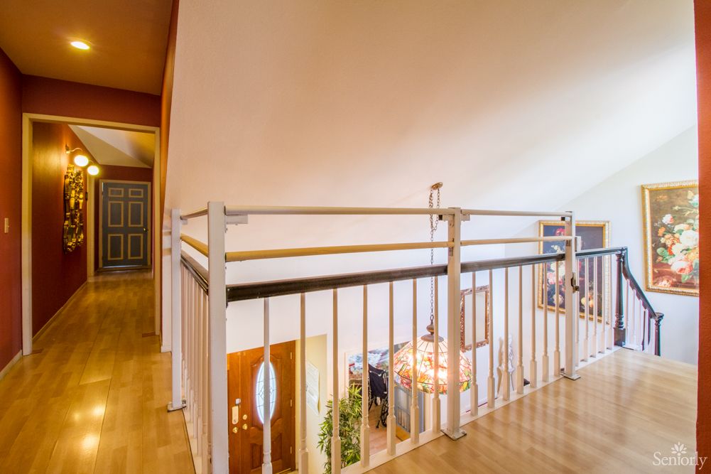 A modern loft interior with a railing and chandelier overlooking stairs.