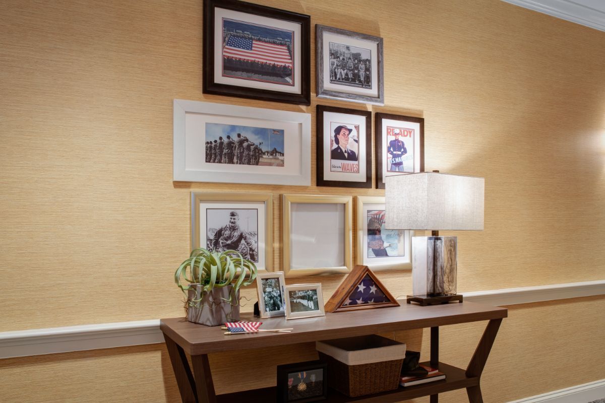 A cozy corner featuring a desk with framed photos and a lamp, complemented by wall art and decorative items.