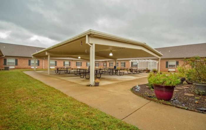 A covered patio area with tables and chairs outside a brick building under an overcast sky.