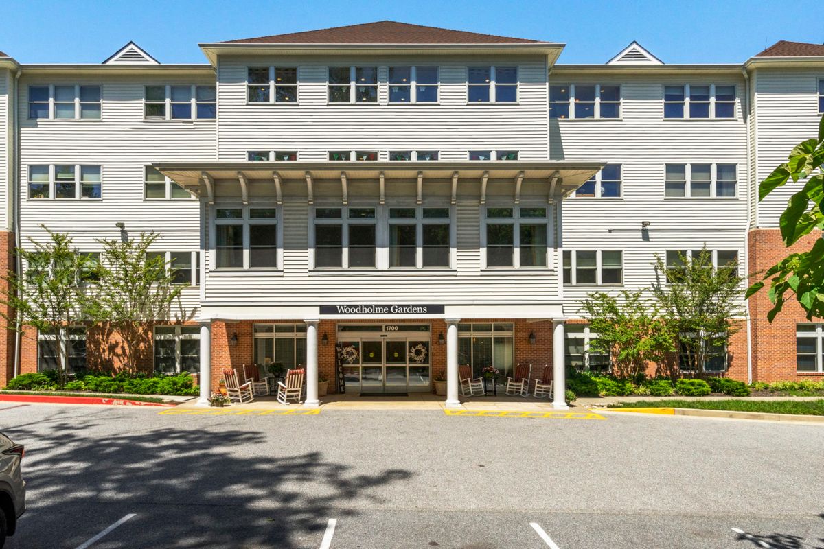 A modern multi-story residential building with a welcoming entrance and adjacent parking area.