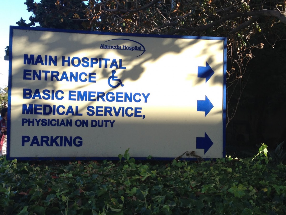 Hospital sign indicating directions to the main entrance and emergency services.