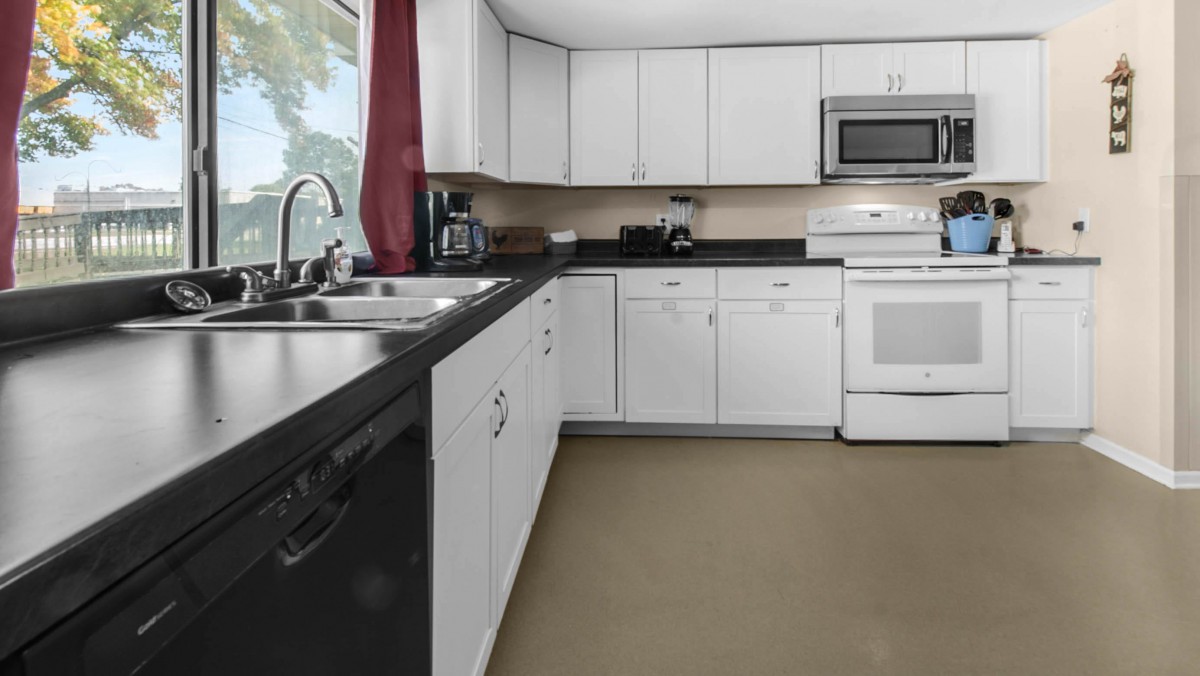 A modern kitchen with white cabinets and a black countertop.