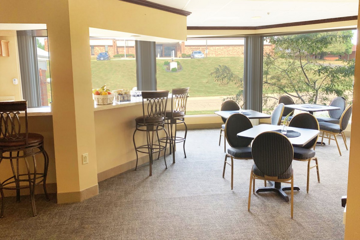 A cozy indoor bar and seating area with natural light streaming through large windows.
