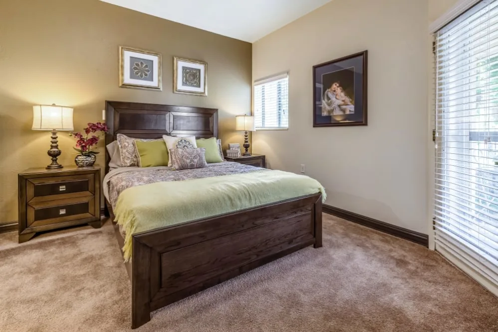 Cozy bedroom with a wooden bed frame, soft bedding, and decorative artwork on the wall.