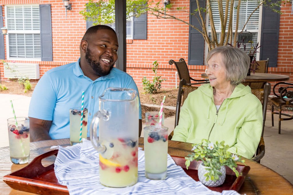 Two people enjoying a conversation over lemonade in an outdoor setting.