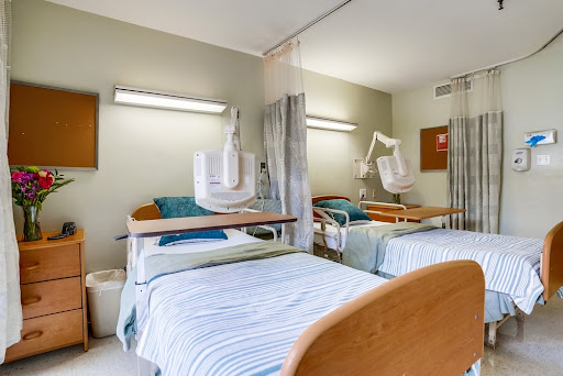 A view of a hospital patient room featuring two beds and medical equipment.