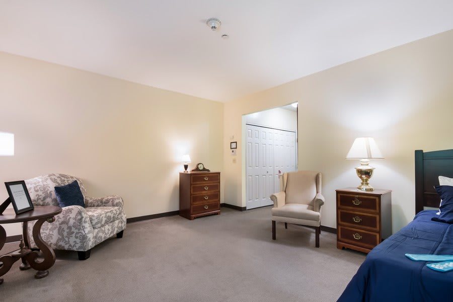 A cozy room with chairs, dressers, and lamps arranged neatly.