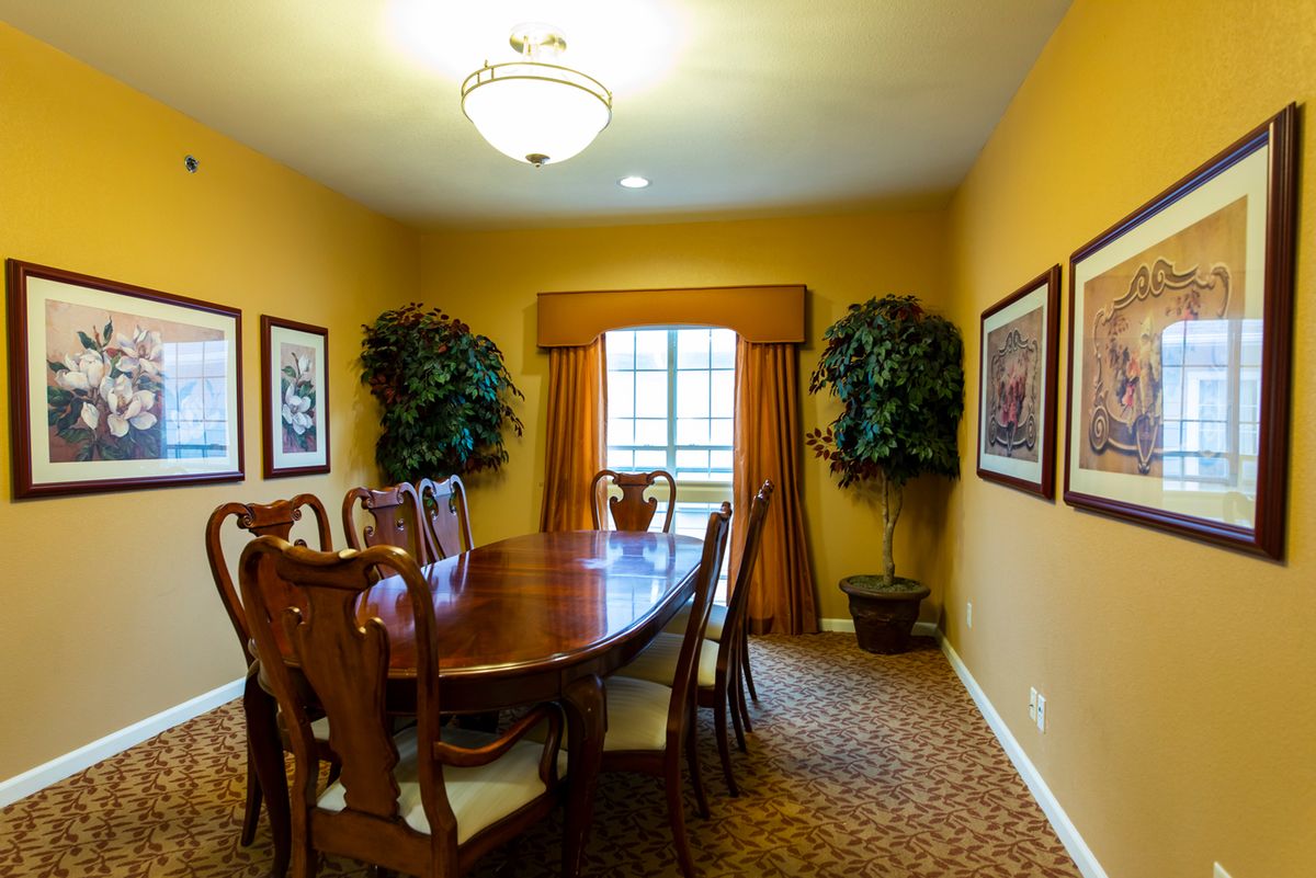 A cozy dining room with a wooden table and chairs, decorated with wall art and indoor plants.