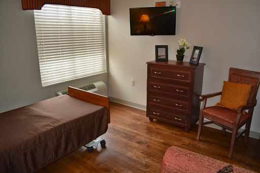 A comfortable hospital patient room featuring a bed, dresser, and television.