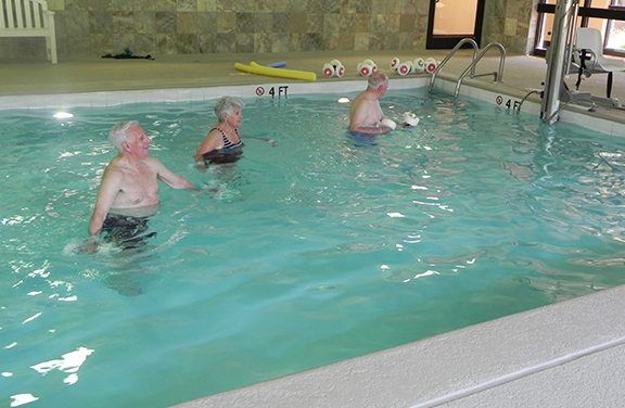 A group of people exercising in an indoor swimming pool.