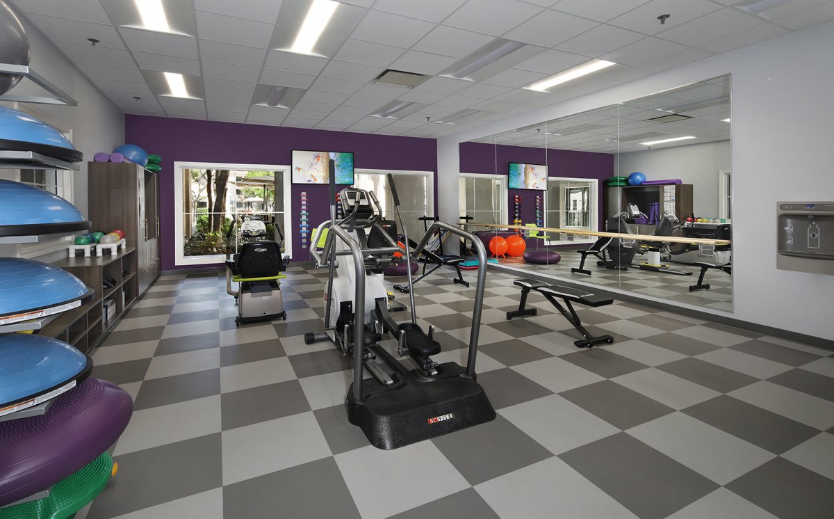 A well-equipped gym with various exercise machines and mirrored walls.