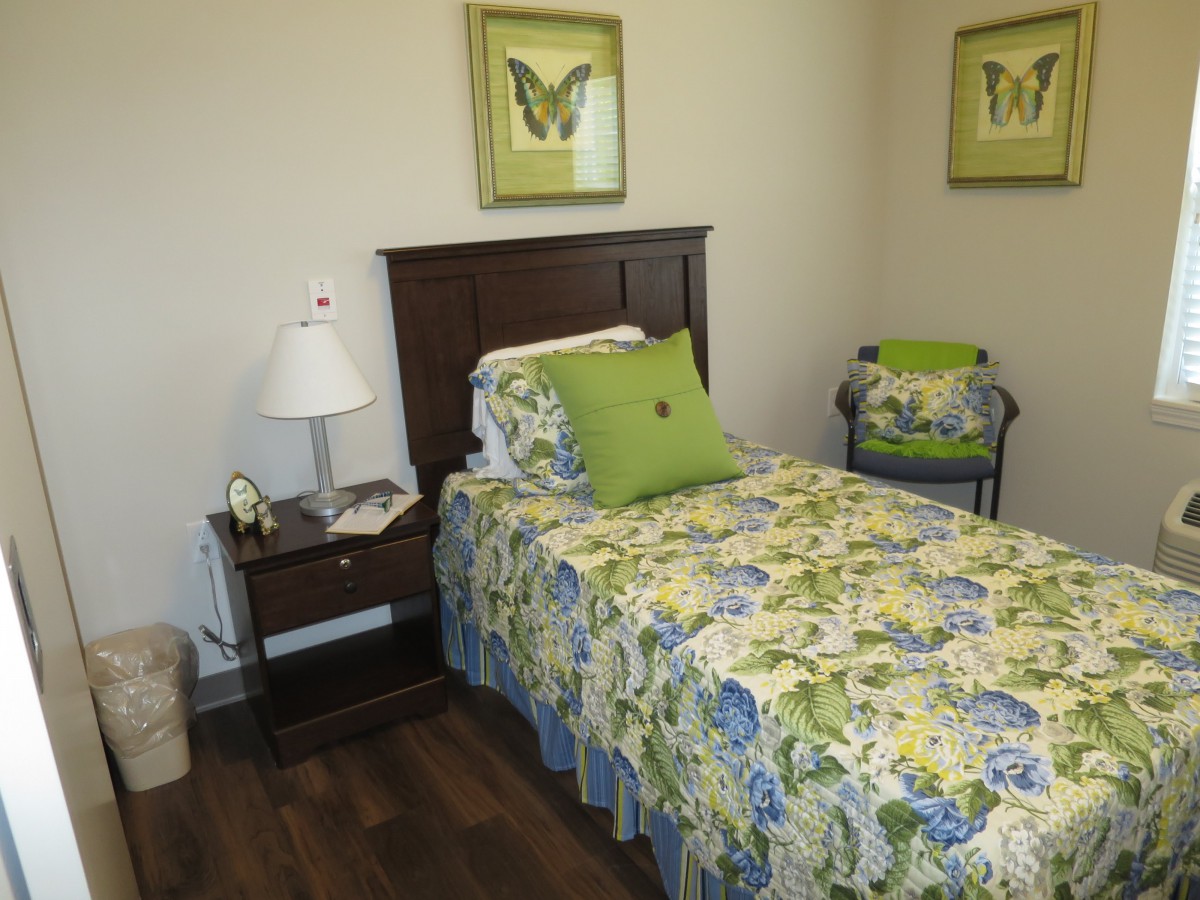 A cozy bedroom with a floral-decorated single bed and matching wall art.