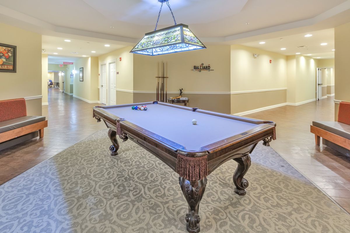 A well-lit recreation room with a classic wooden pool table and stylish decor.