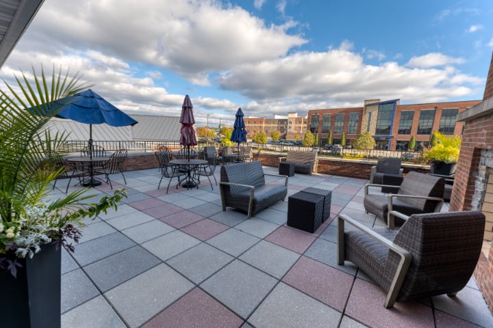 A rooftop patio with comfortable seating and umbrellas under a partly cloudy sky.