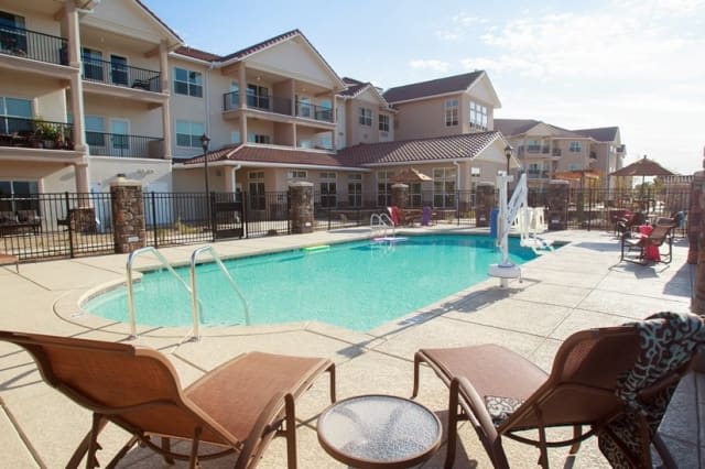 A sunny day at a residential apartment complex featuring an outdoor swimming pool and lounge chairs.