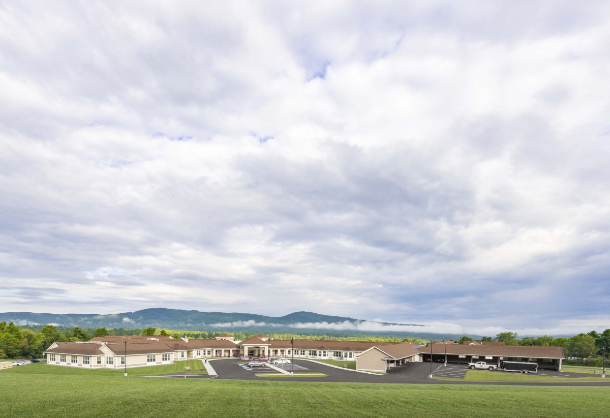 A school building surrounded by green fields under a cloudy sky.