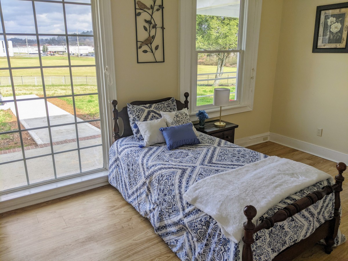 A cozy bedroom with a single bed and a large window letting in natural light.