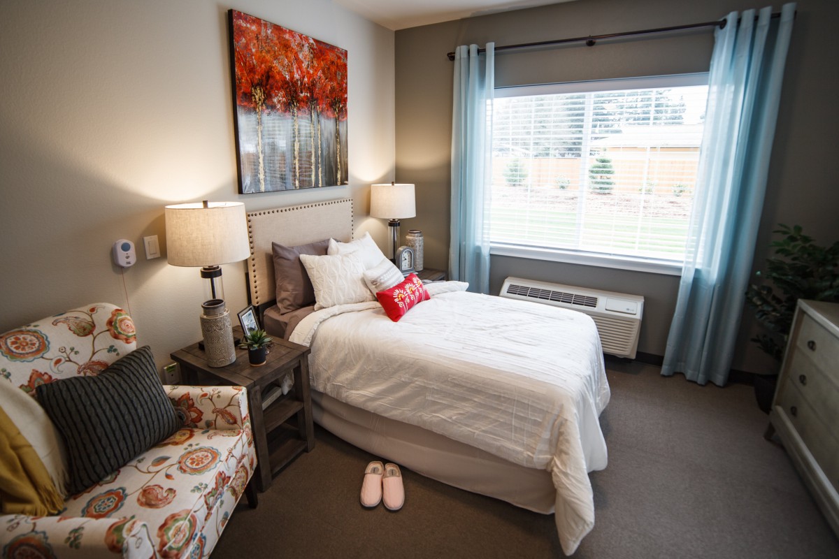 A cozy bedroom with a neatly made bed, decorated with soft lighting and warm colors.