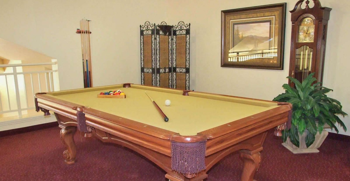 A home game room featuring a billiard table with a cue stick and balls ready for play.
