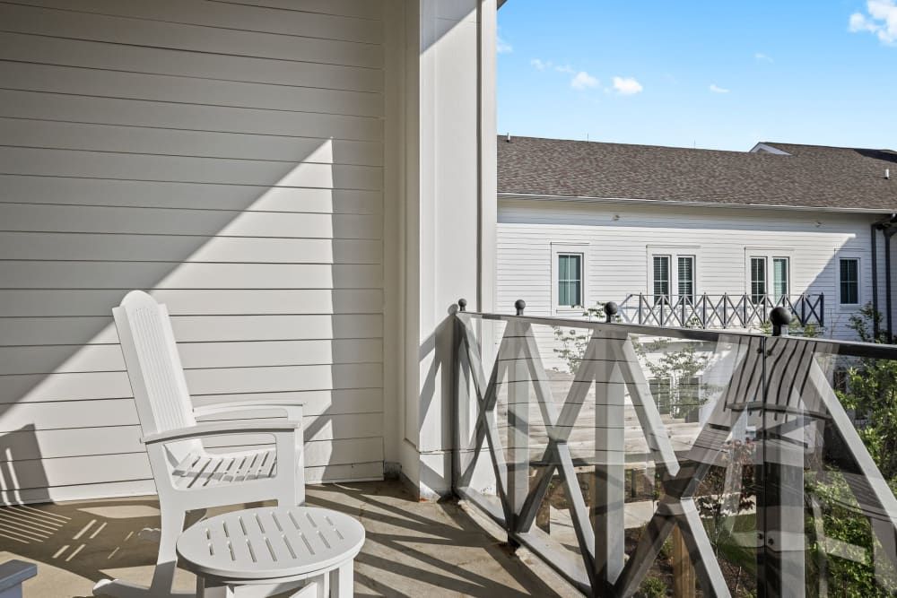 A sunny balcony with a white chair and decorative railing.