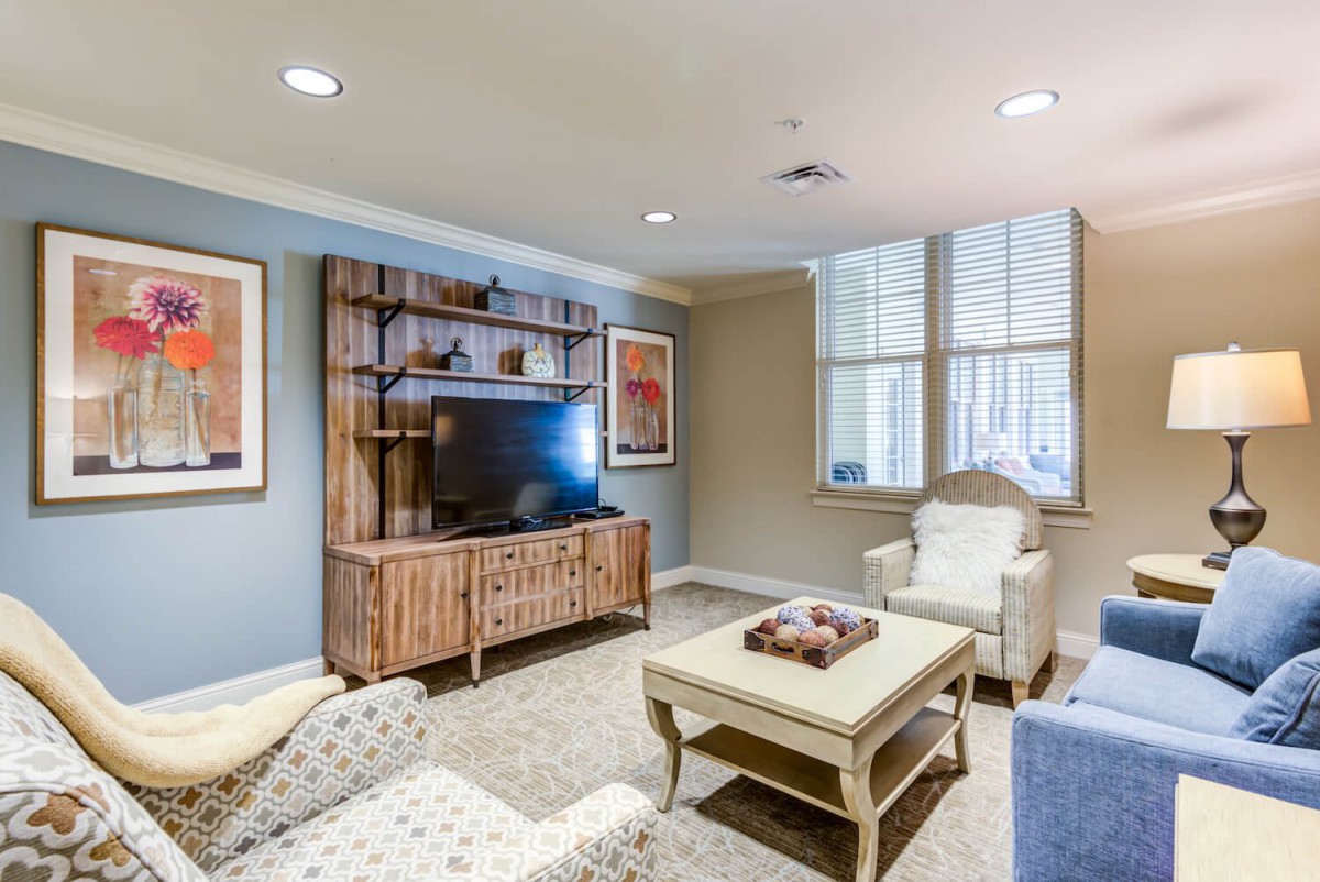 A cozy living room featuring a television set within a wooden cabinet, stylish armchairs, and a coffee table adorned with decorative items.
