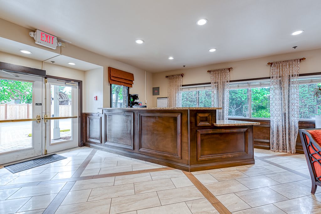 A spacious hotel lobby with a wooden reception desk and large windows providing natural light.