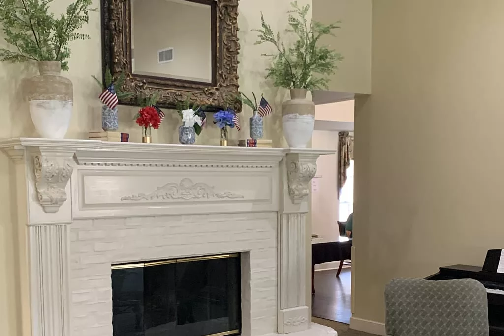 A beautifully decorated fireplace with a mirror and vases of flowers.