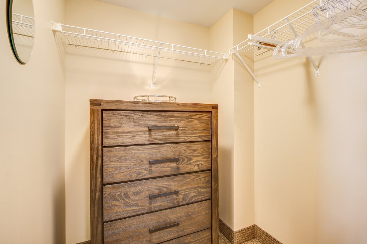A closet featuring a wooden dresser and wire shelving for storage.