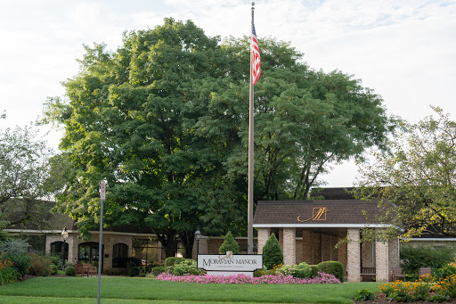 A welcoming entrance featuring a flag, landscaped surroundings, and a sign.