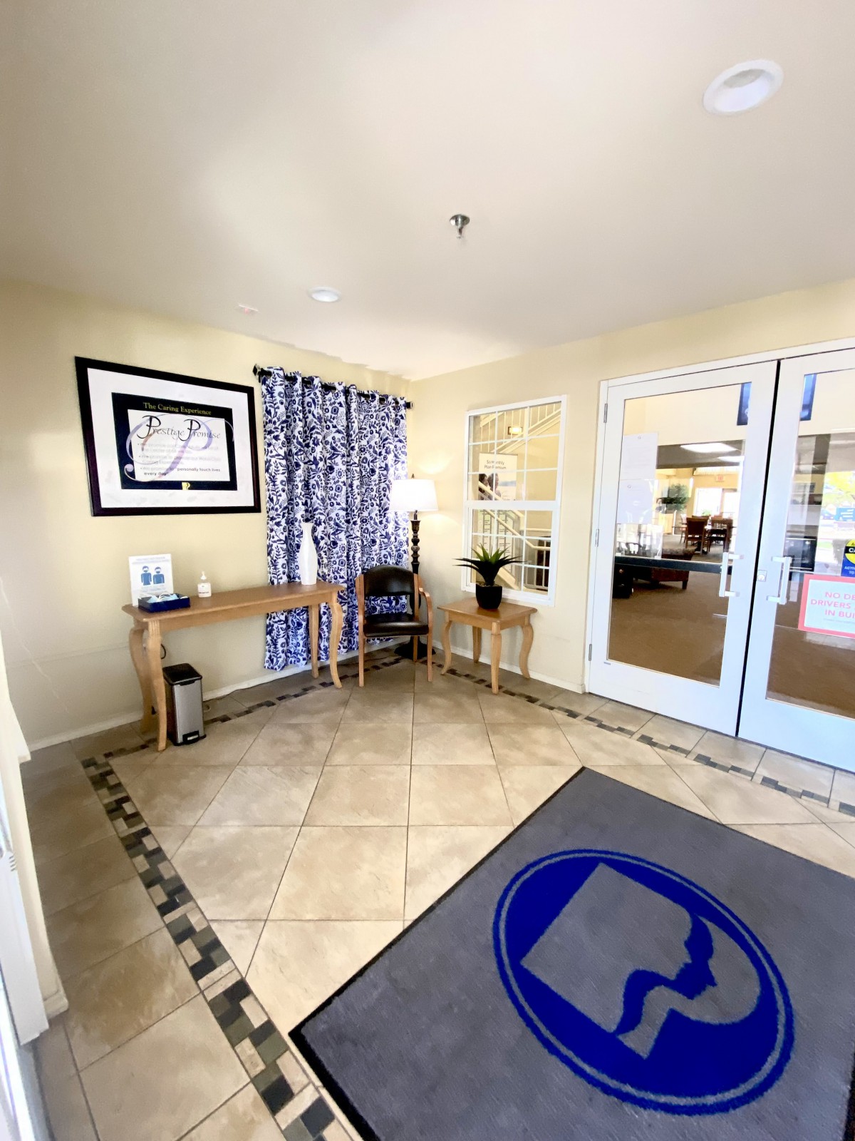 A bright and welcoming lobby entrance with decorative elements, a console table, and double doors leading to another room.