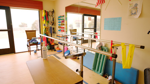 A well-equipped physical therapy room featuring parallel bars and various exercise tools.