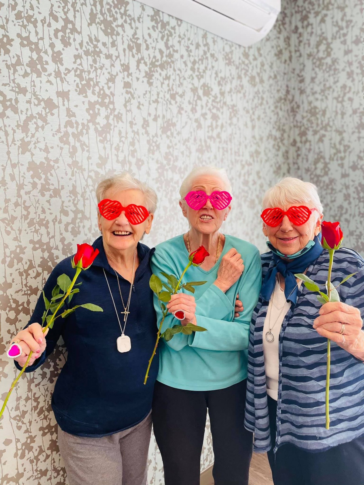 Three friends enjoying a fun moment with heart-shaped glasses and roses.