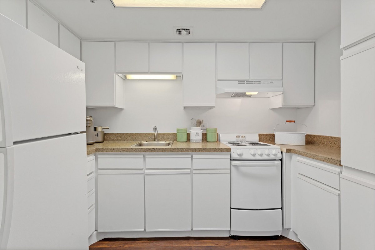 A modern kitchen with white cabinets and standard appliances.