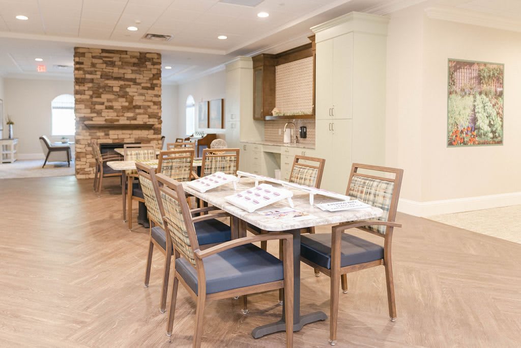 A modern dining area with neatly arranged tables and chairs, featuring light-colored walls and a stone accent wall.