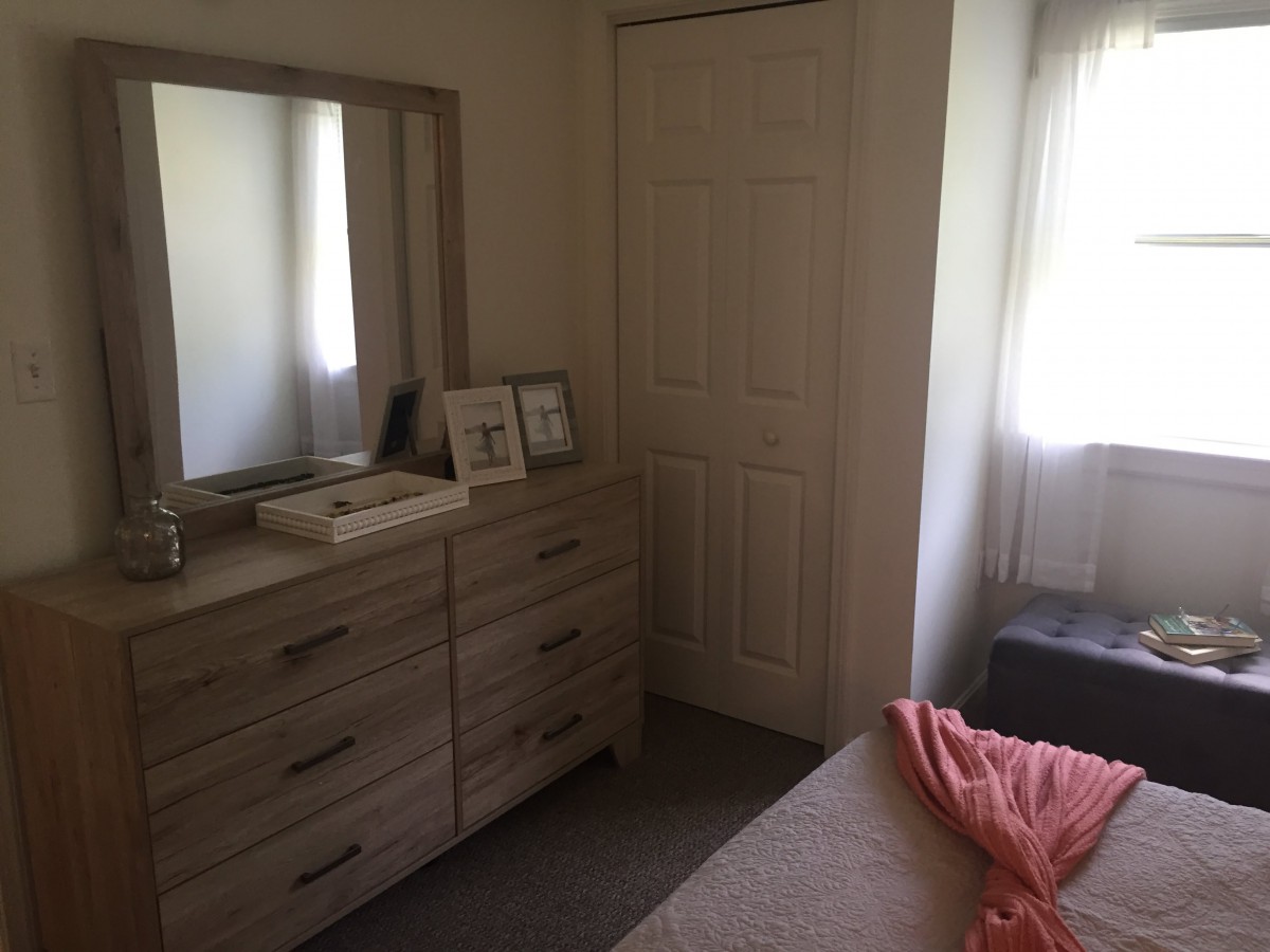 Cozy bedroom with a dresser and mirror by the window.