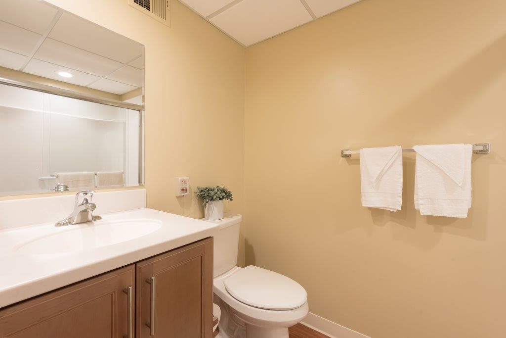 A minimalist bathroom with a sink, toilet, and mirror.