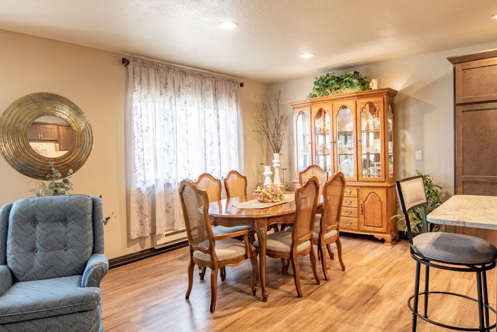 A cozy dining room with a wooden table, chairs, and a display cabinet.