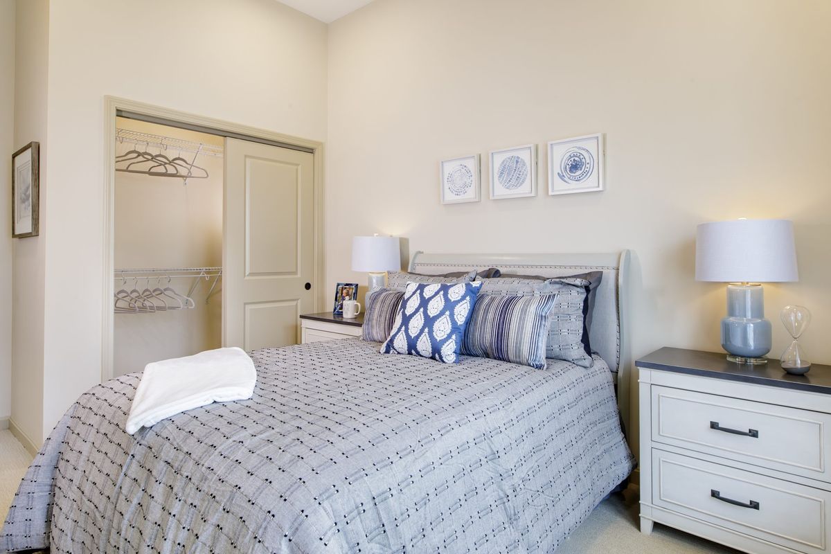 A cozy and well-decorated bedroom with a neatly made bed, nightstands, lamps, and minimalist wall art.