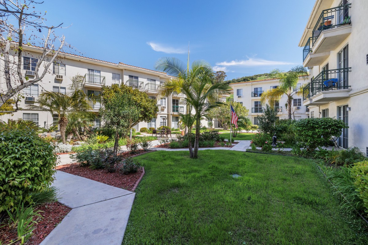 A beautiful apartment complex with lush gardens and palm trees.