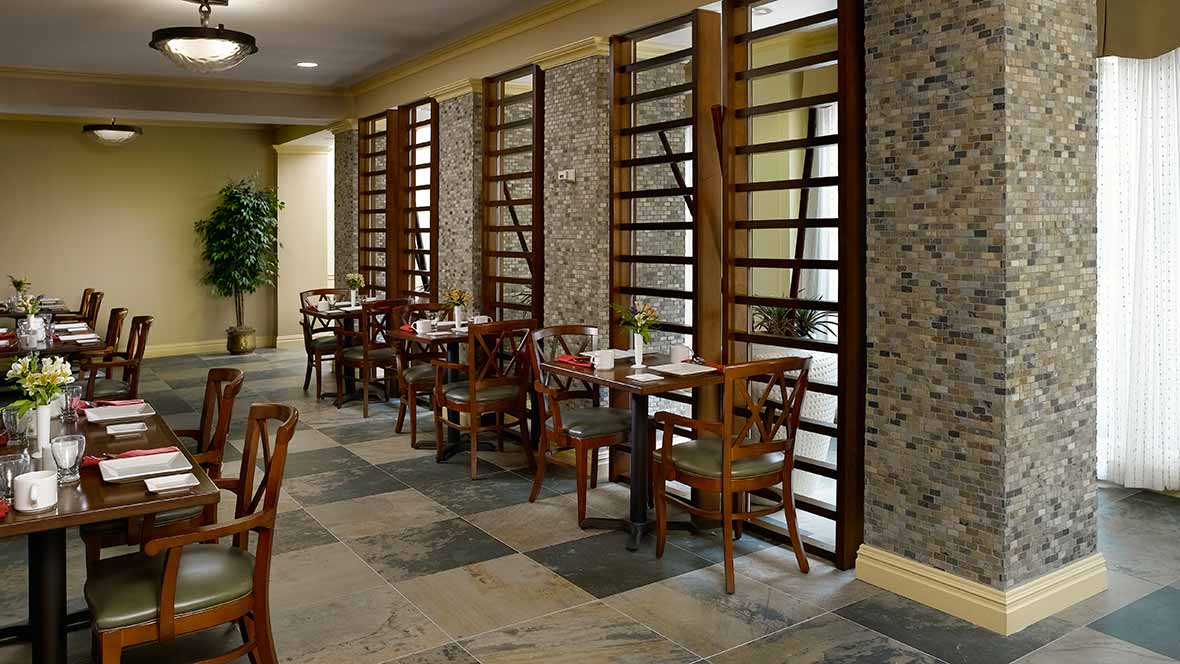 A cozy restaurant dining area with wooden tables and chairs, featuring stylish decor.