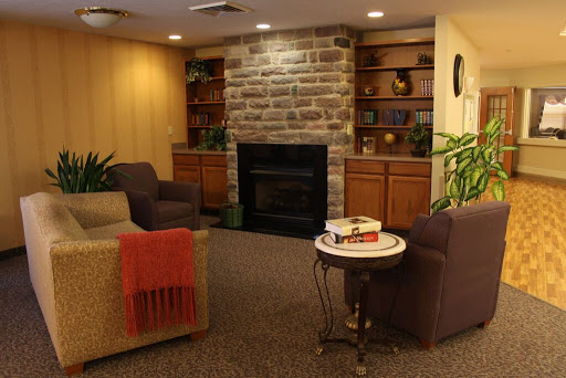 A cozy living room featuring a stone fireplace, comfortable seating, and bookshelves filled with books.