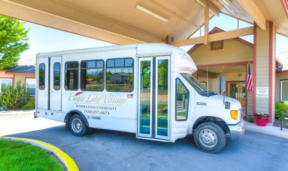 A white shuttle bus parked under a building canopy.