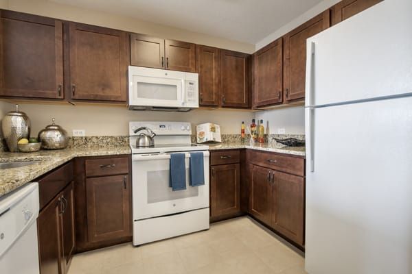 A modern kitchen featuring wooden cabinets and white appliances.