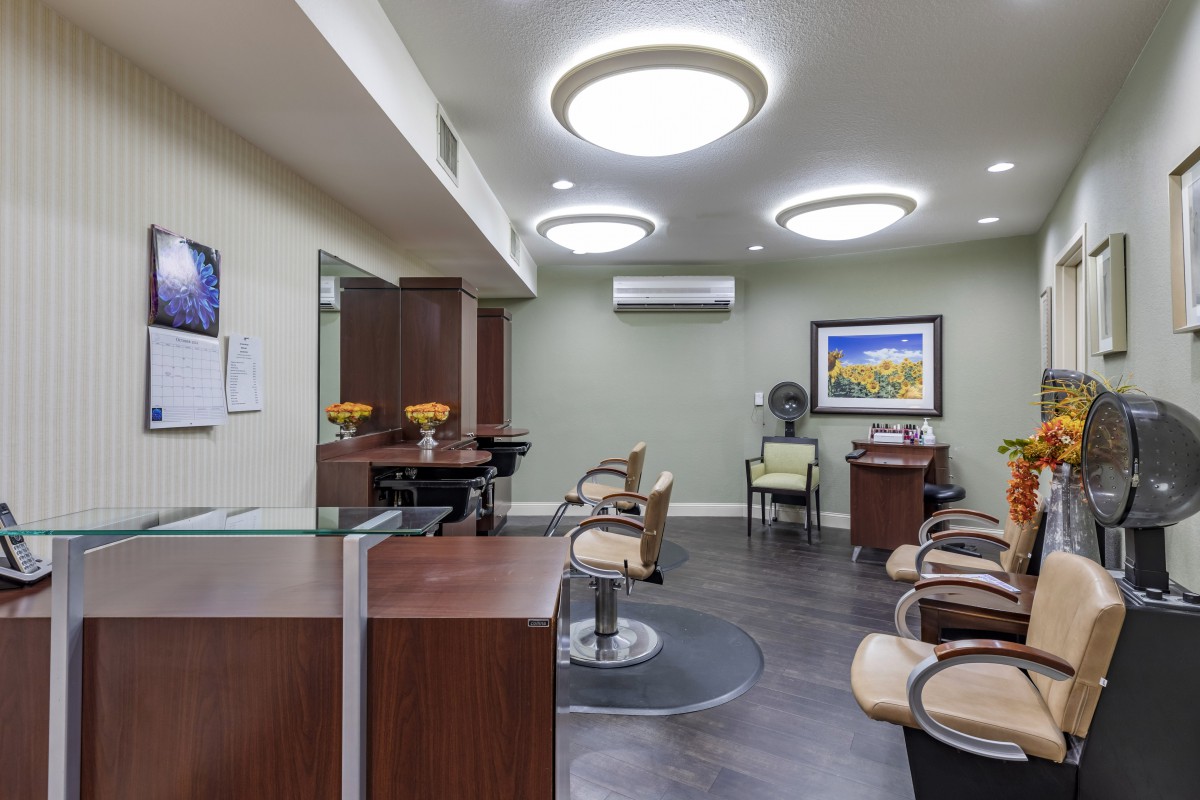 A modern salon interior with styling chairs, a reception desk, and contemporary lighting.