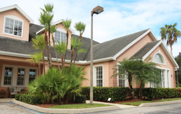 A suburban house with palm trees and well-manicured landscaping.